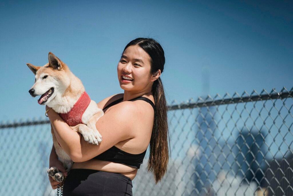 Cheerful ethnic lady with dog during training in park